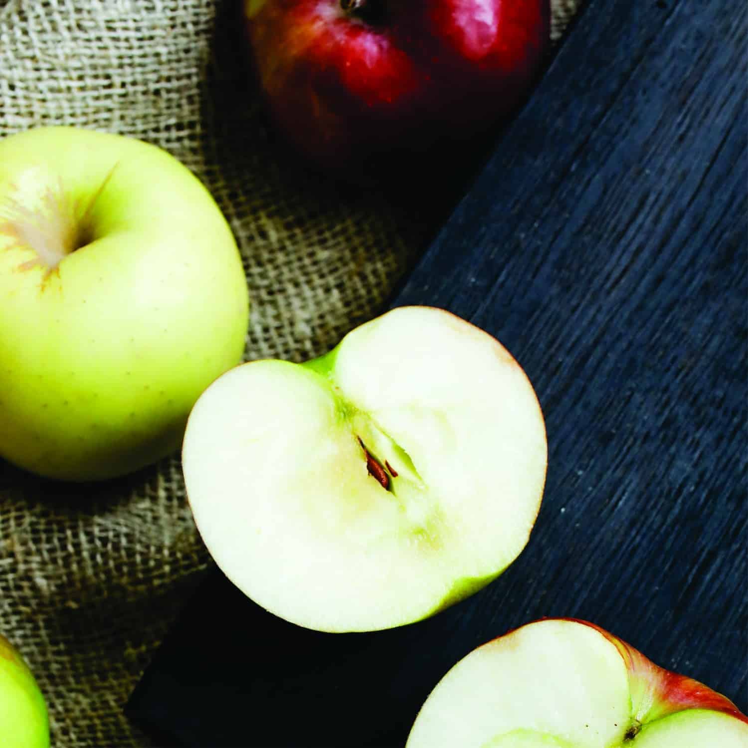 green and red apples with one apple sliced open