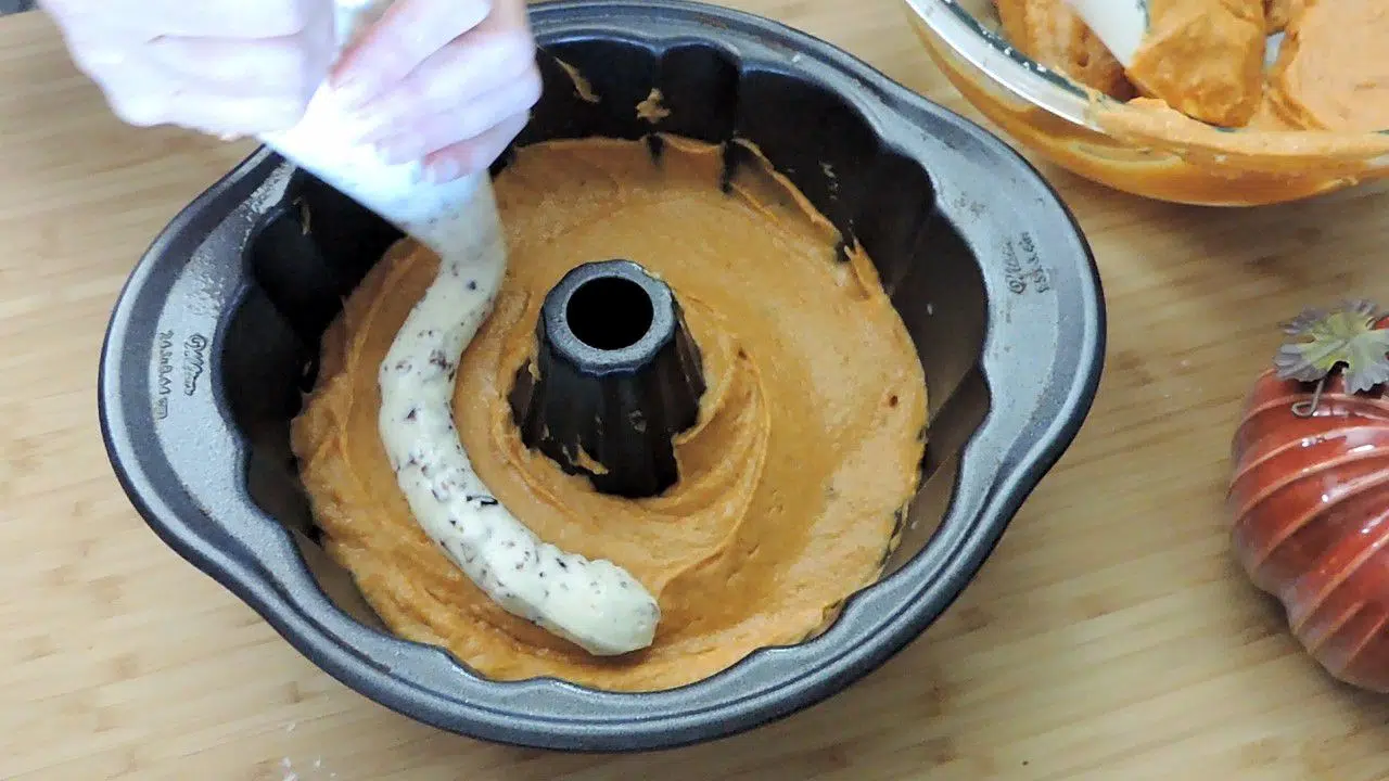 Bundt cake pan with unbaked pumpkin batter and cream cheese filling