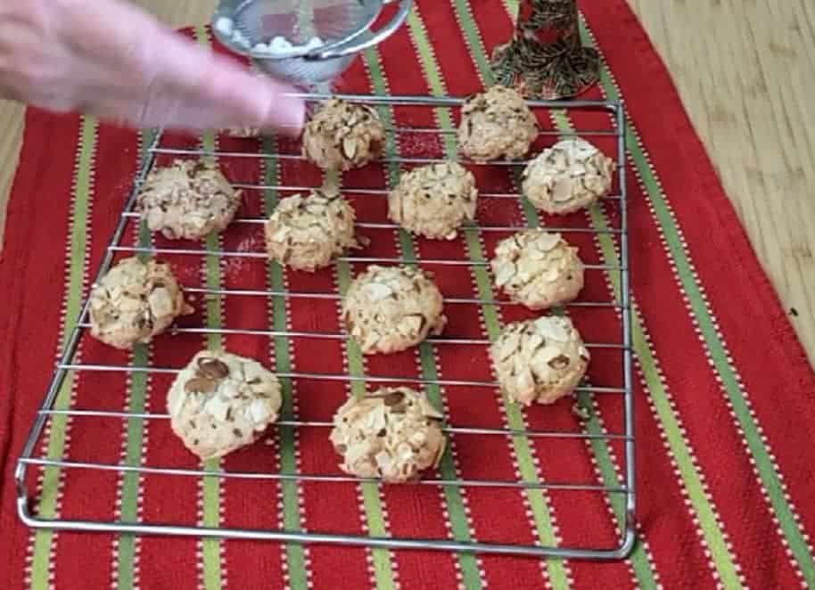 adding powdered sugar to the top of almond paste cookies 