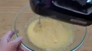whipping egg yolks in a bowl for custard sauce