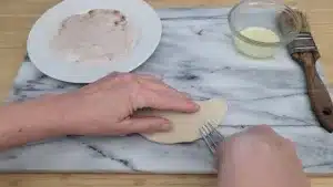 sealing dessert empanada with fork