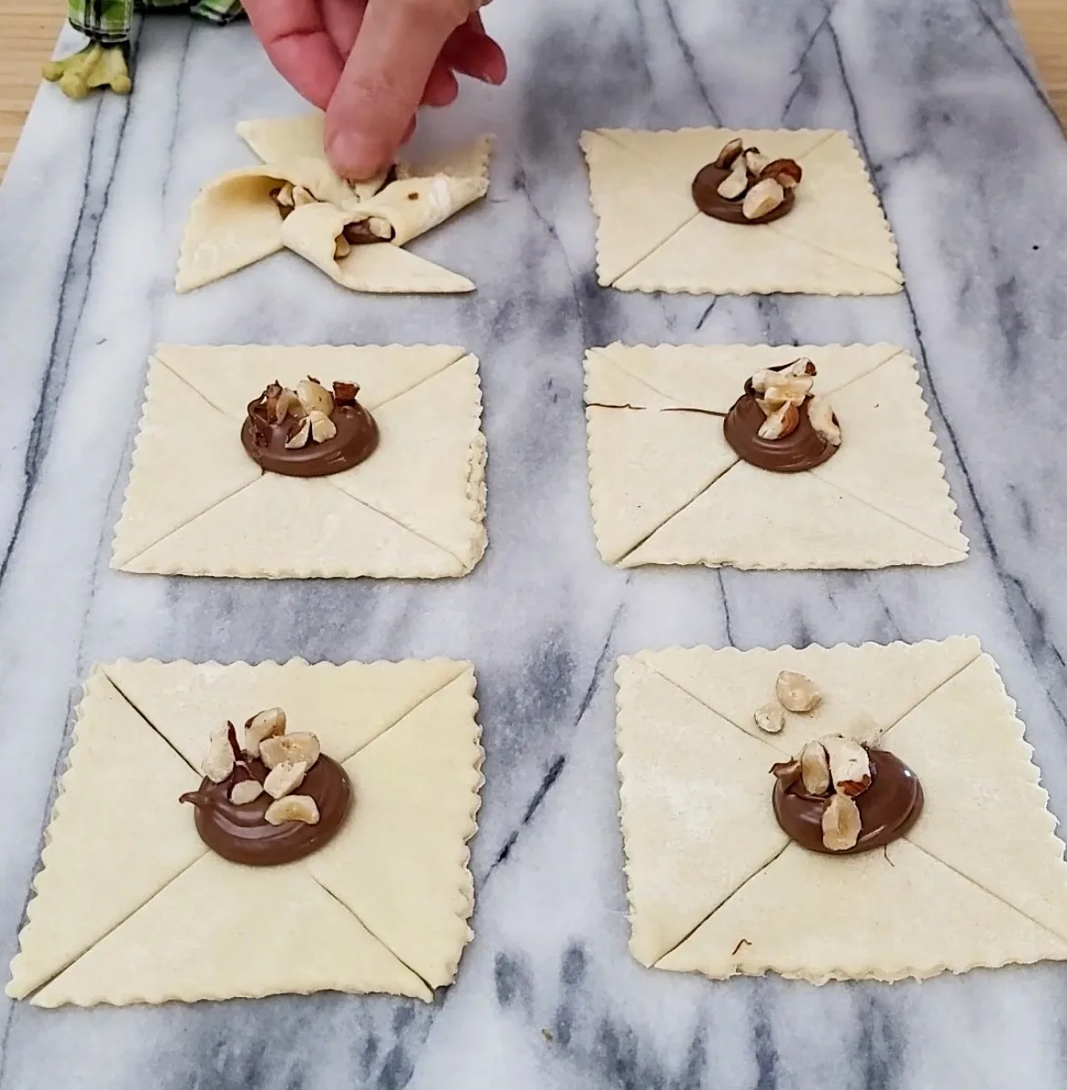 filling and folding puff pastry pinwheels with Nutella and hazelnuts
