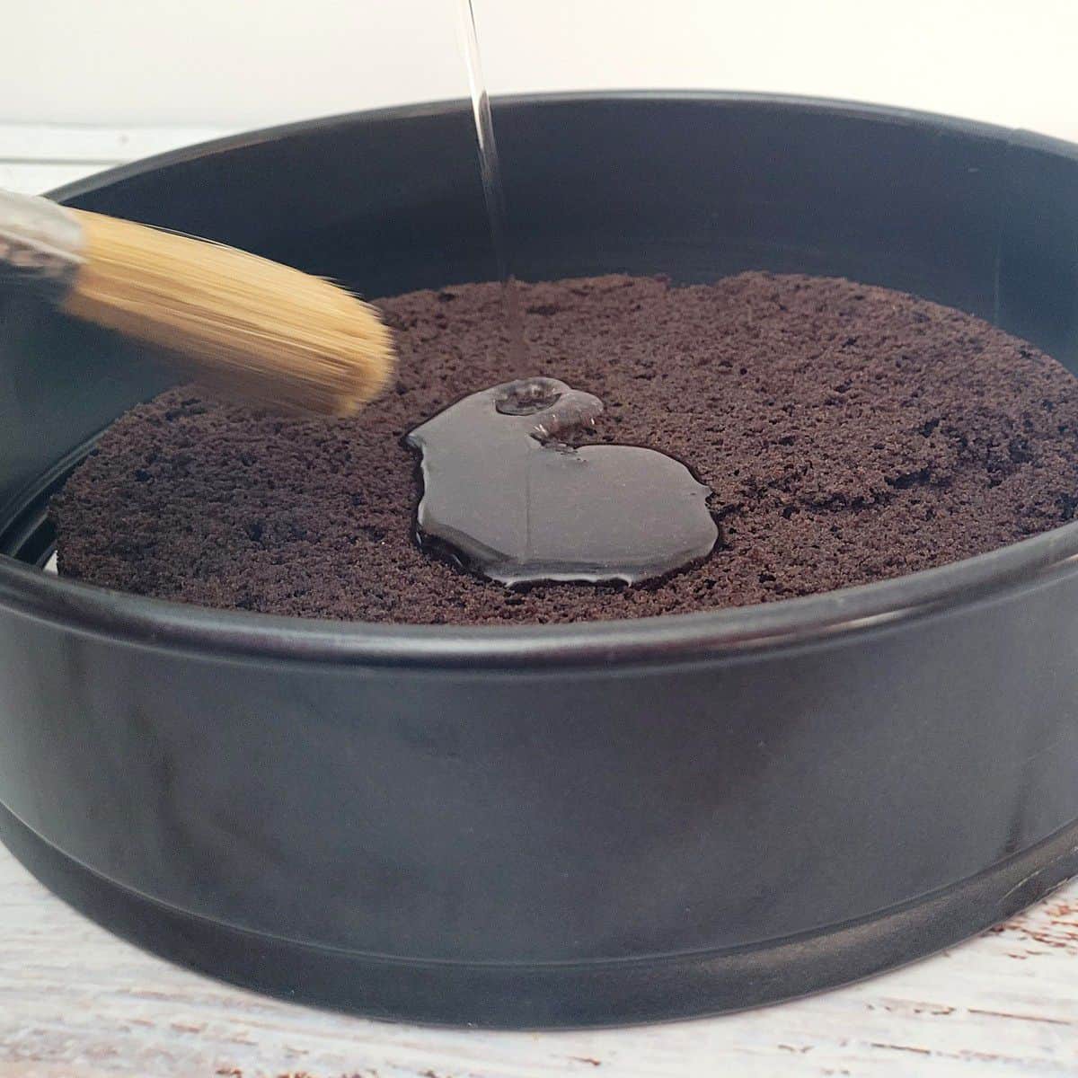 adding simple syrup to chocolate cake