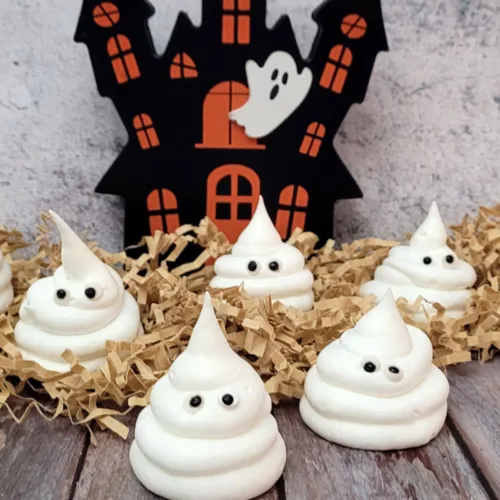 meringue ghosts filled with chocolate and almonds with a haunted house in background