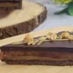 slice of caramel peanut butter tart on a wooden serving plate