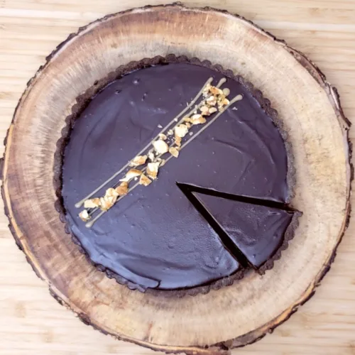 overhead view of a caramel peanut butter tart with one slice cut out