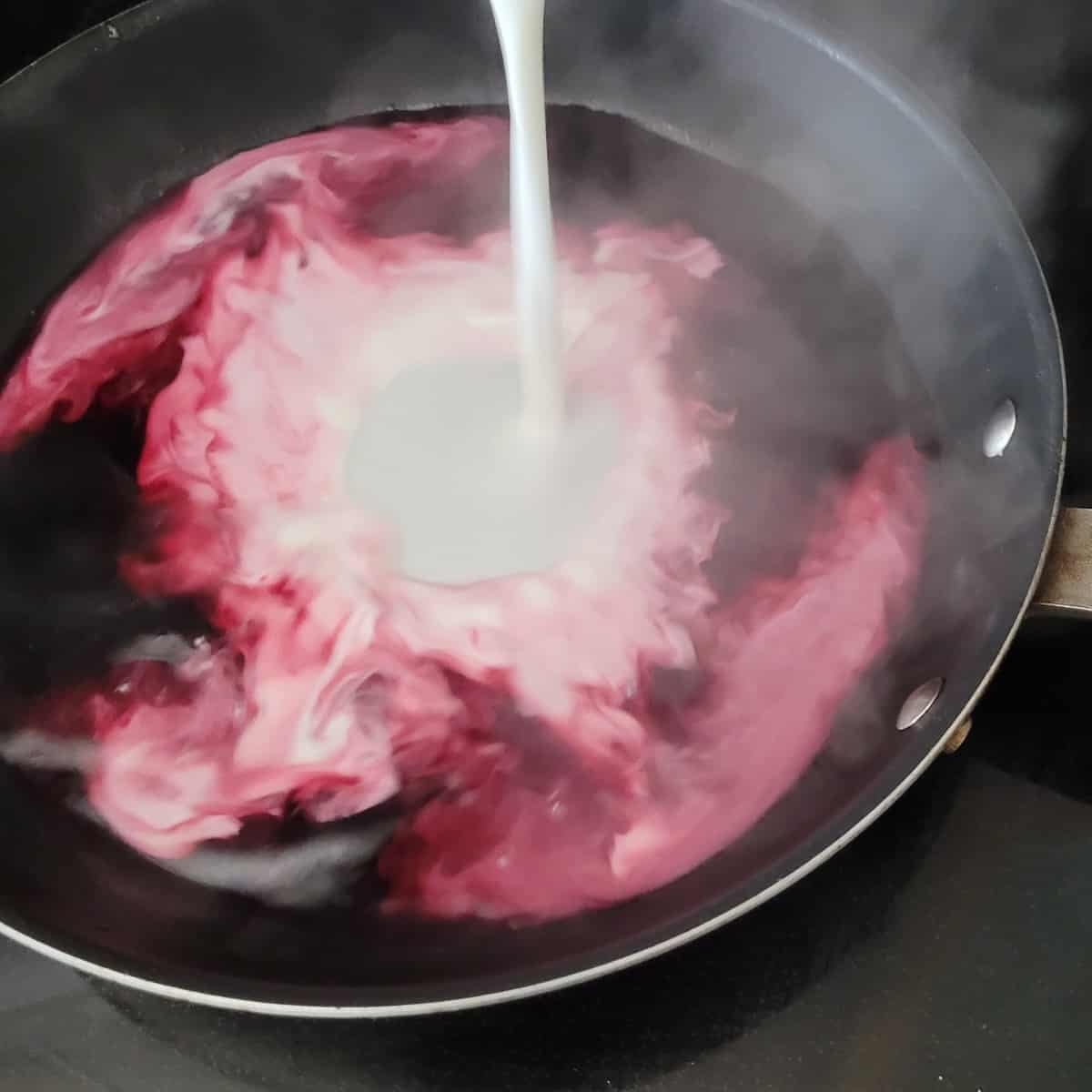 cornstarch being added to saucepan with blueberry juice to make pie filling