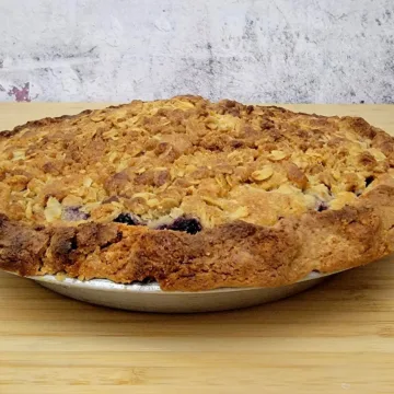 full blueberry crumble pie made with frozen blueberries sitting on a wooden countertop