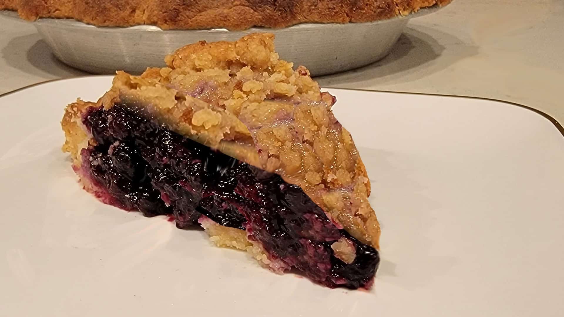 slice of blueberry crumble pie with the pie pan in background