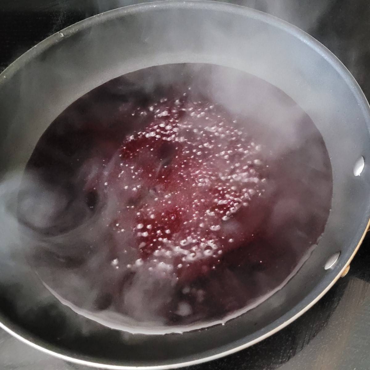 blueberry juice and sugar boiling in a saucepan