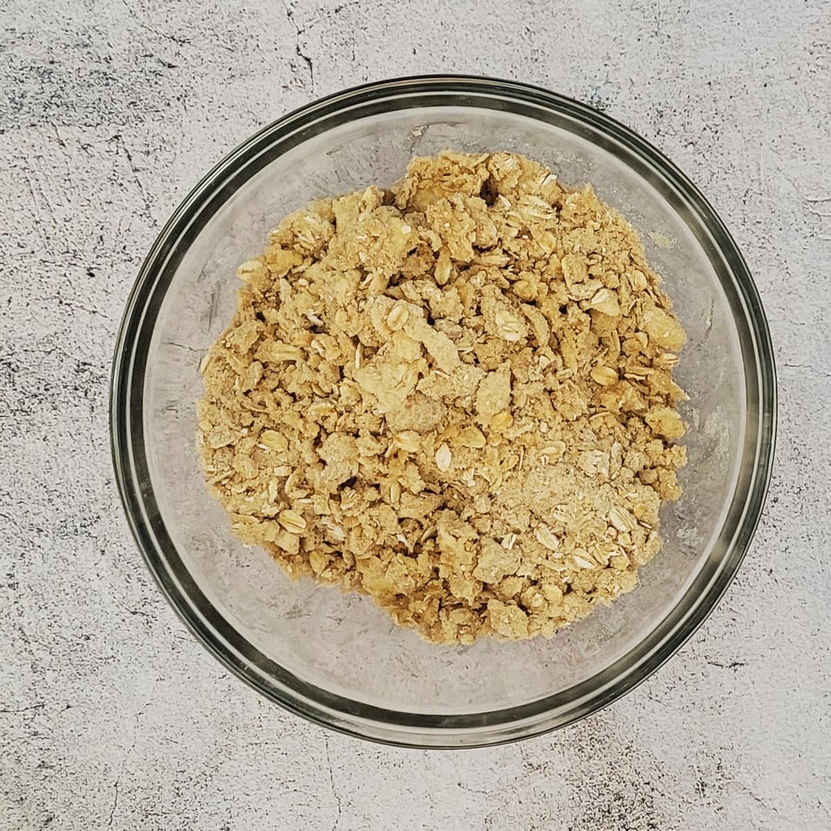 glass bowl with all ingredients for crumble pie topping mixed together