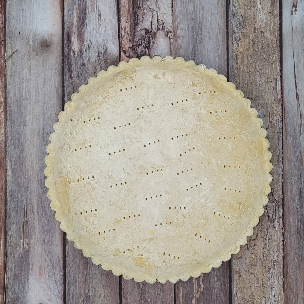 unbaked pie crust with holes poked in dough prior to par-baking