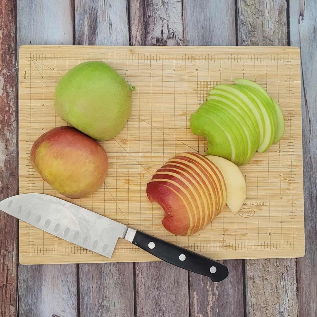 sliced red and green apple on a wooden cutting board
