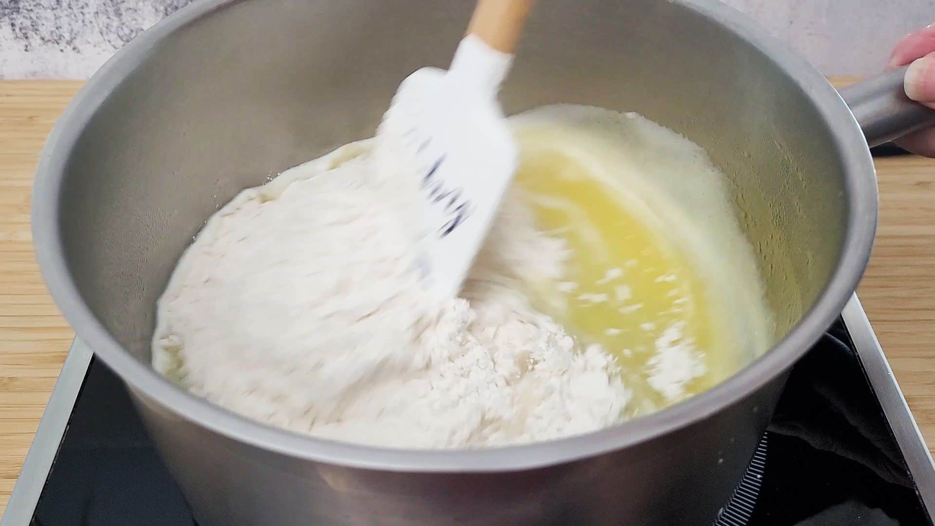 adding flour to saucepan with water, butter and salt