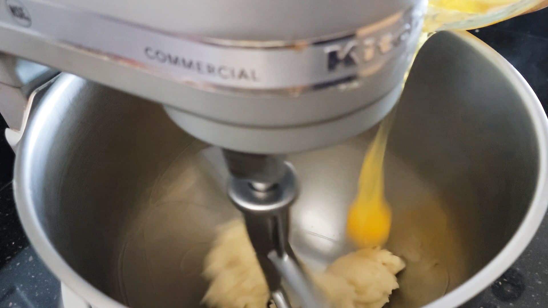 adding eggs to stand mixer with pate a choux in bowl