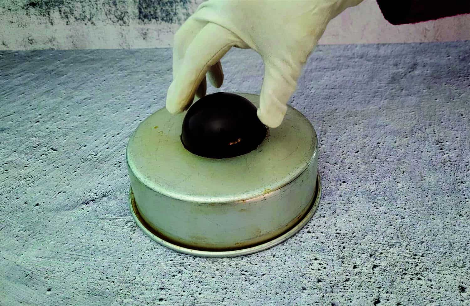 placing chocolate sphere on a warm cake pan to slightly melt the chocolate