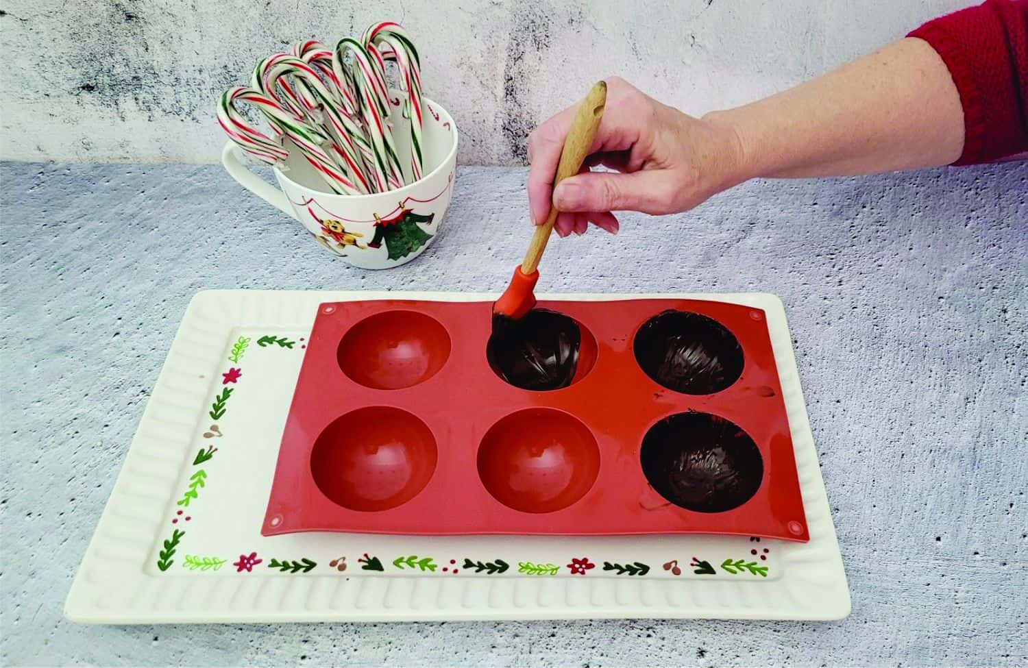 applying chocolate inside of sphere mold for the first coating