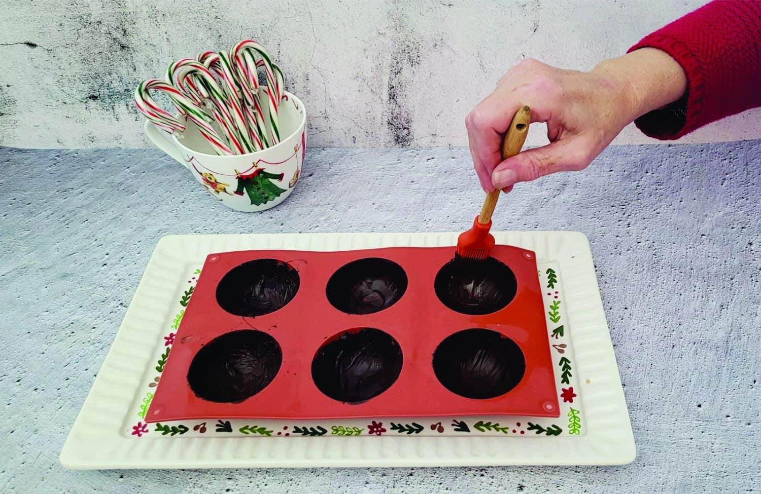 applying chocolate inside of sphere mold for the second coating