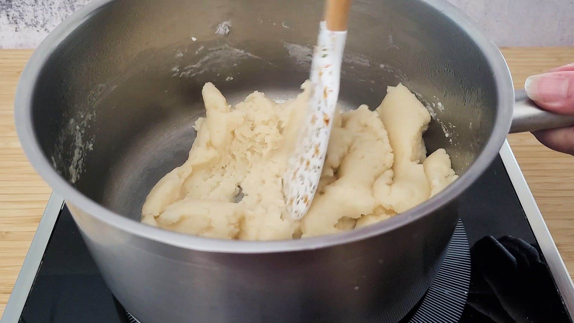 stirring pate a choux paste in a saucepan with a spatula