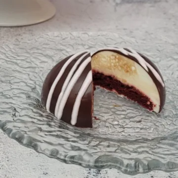 closeup image of an individual serving of red velvet cake with the center cut open to show the cream cheese mousse