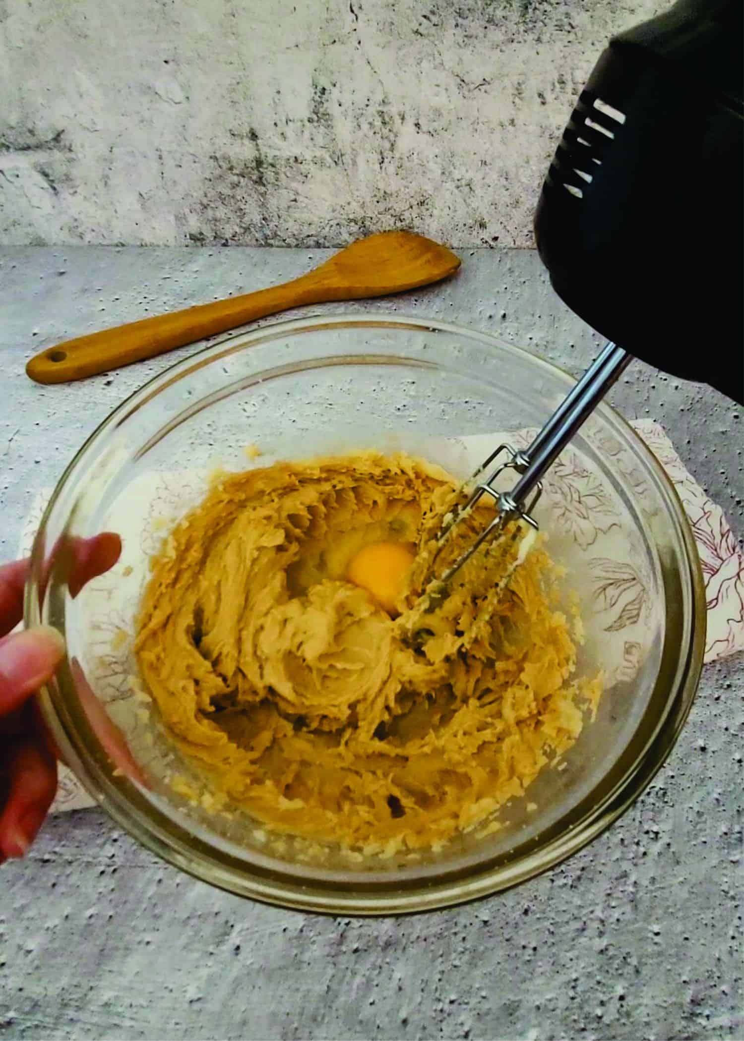 mixing an egg into cookie dough using a hand mixer