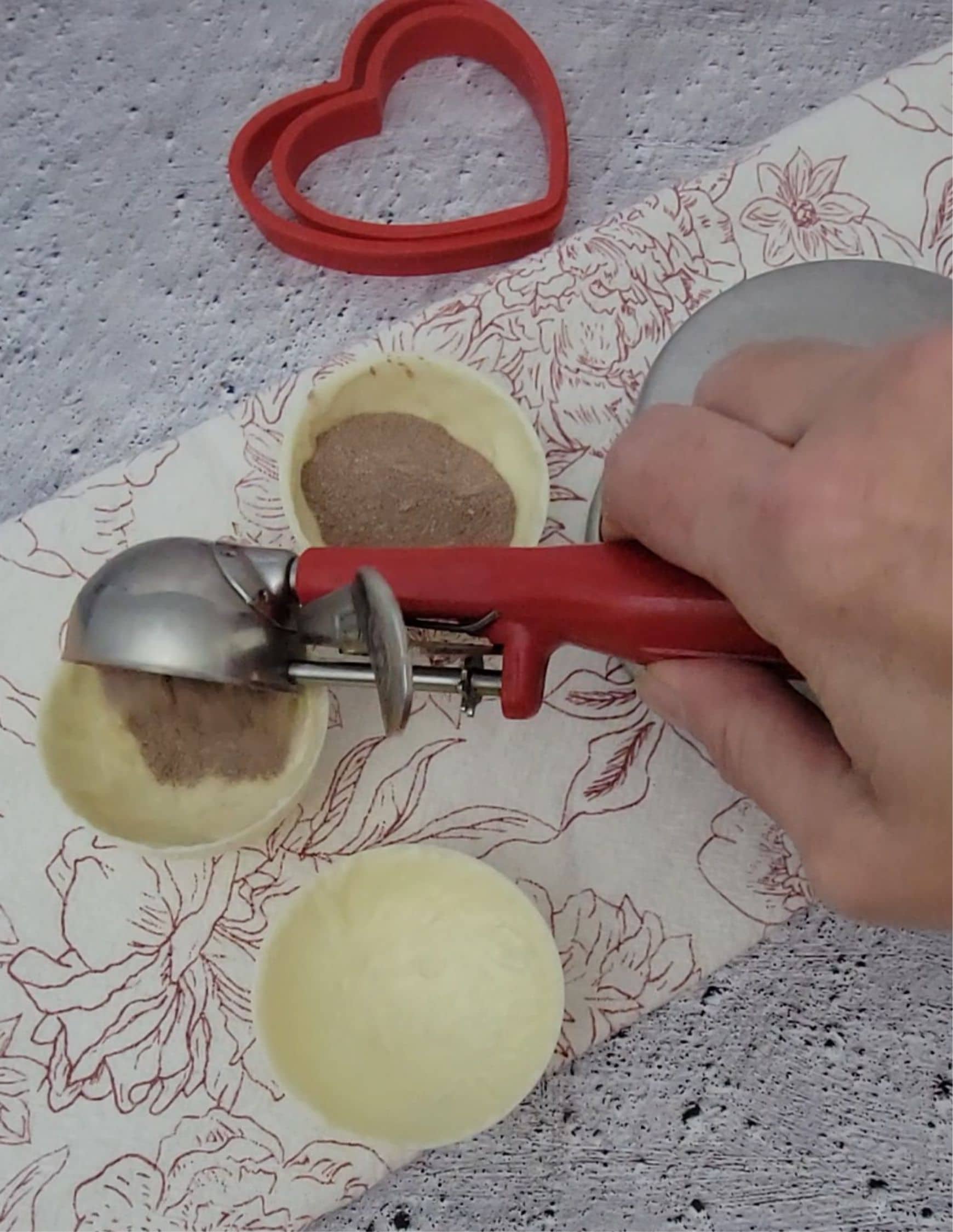 using a scoop to add hot cocoa mix to white chocolate half spheres