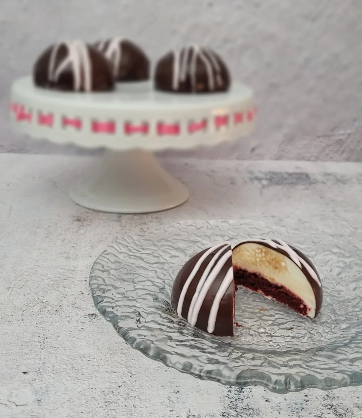 red velvet mini valentine's cake on a glass plate with three more cakes on a cake stand