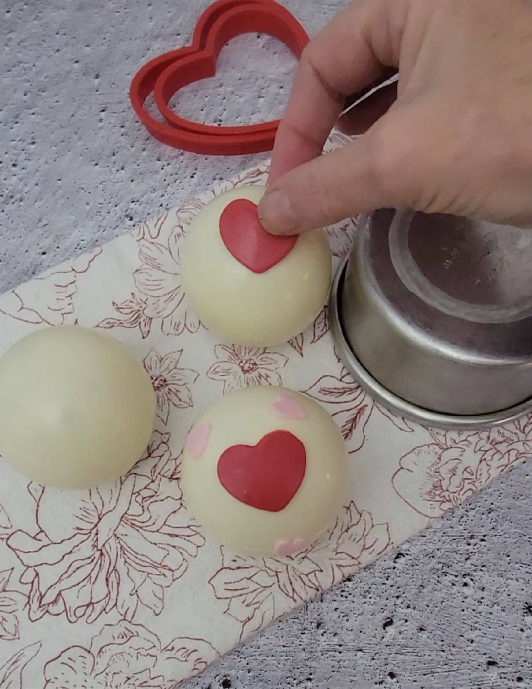 applying fondant hearts to white chocolate cocoa bombs