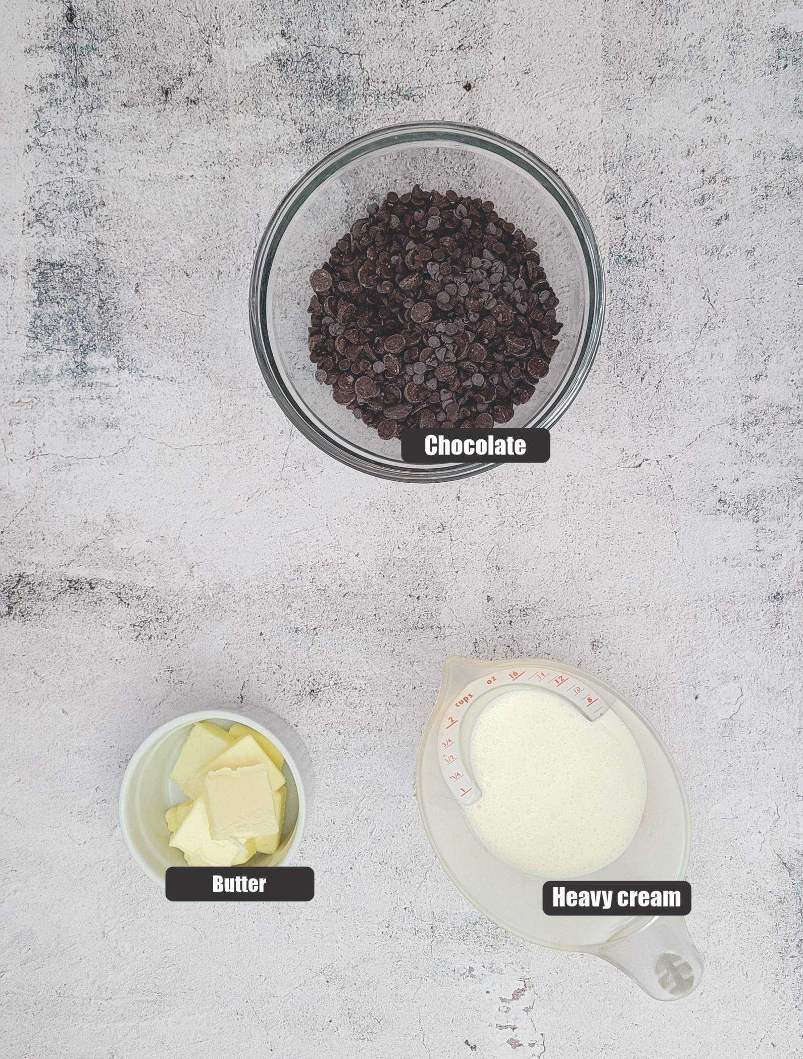 overhead view of ingredients needed to make chocolate ganache including chocolate, butter and heavy cream