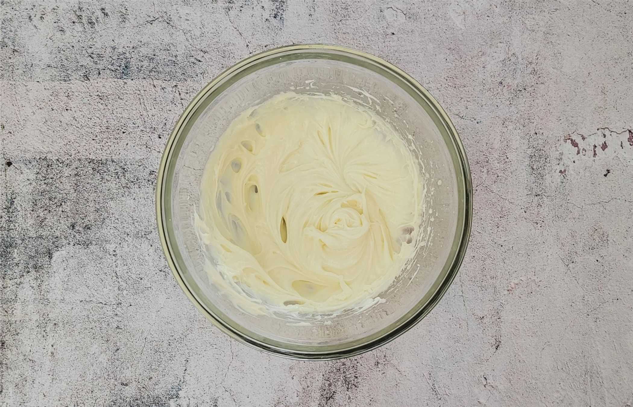 overhead view of cream cheese and granulated sugar mixed together in a bowl to make a cream cheese mousse filling