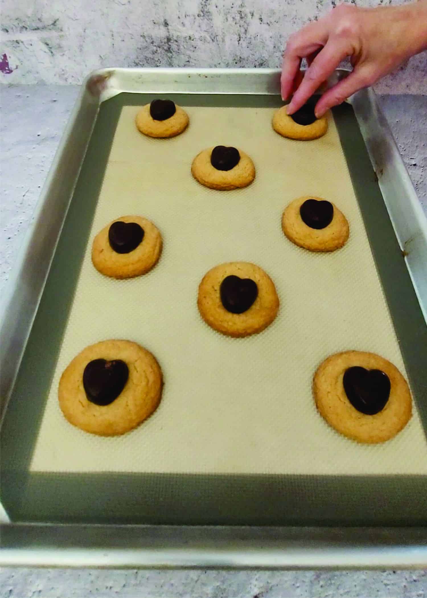 placing chocolate hearts on top of warm peanut butter cookies