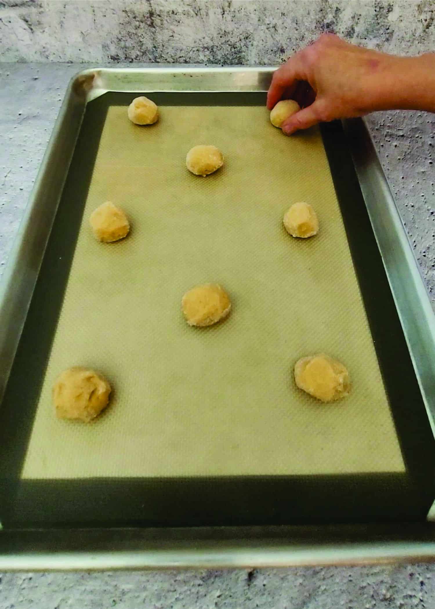 placing peanut butter cookie dough balls on a baking sheet