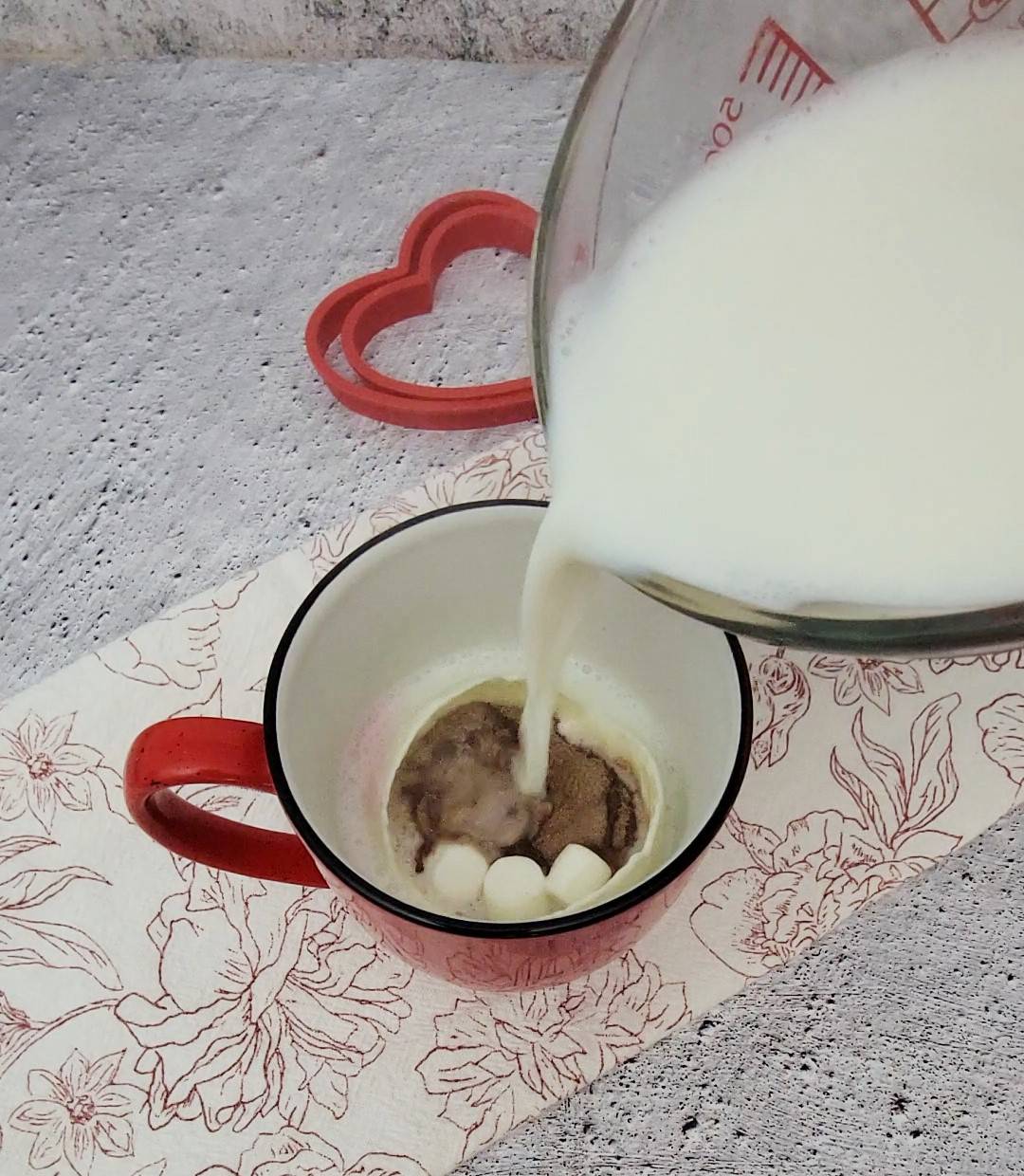 pouring hot milk into a mug to melt hot chocolate bomb