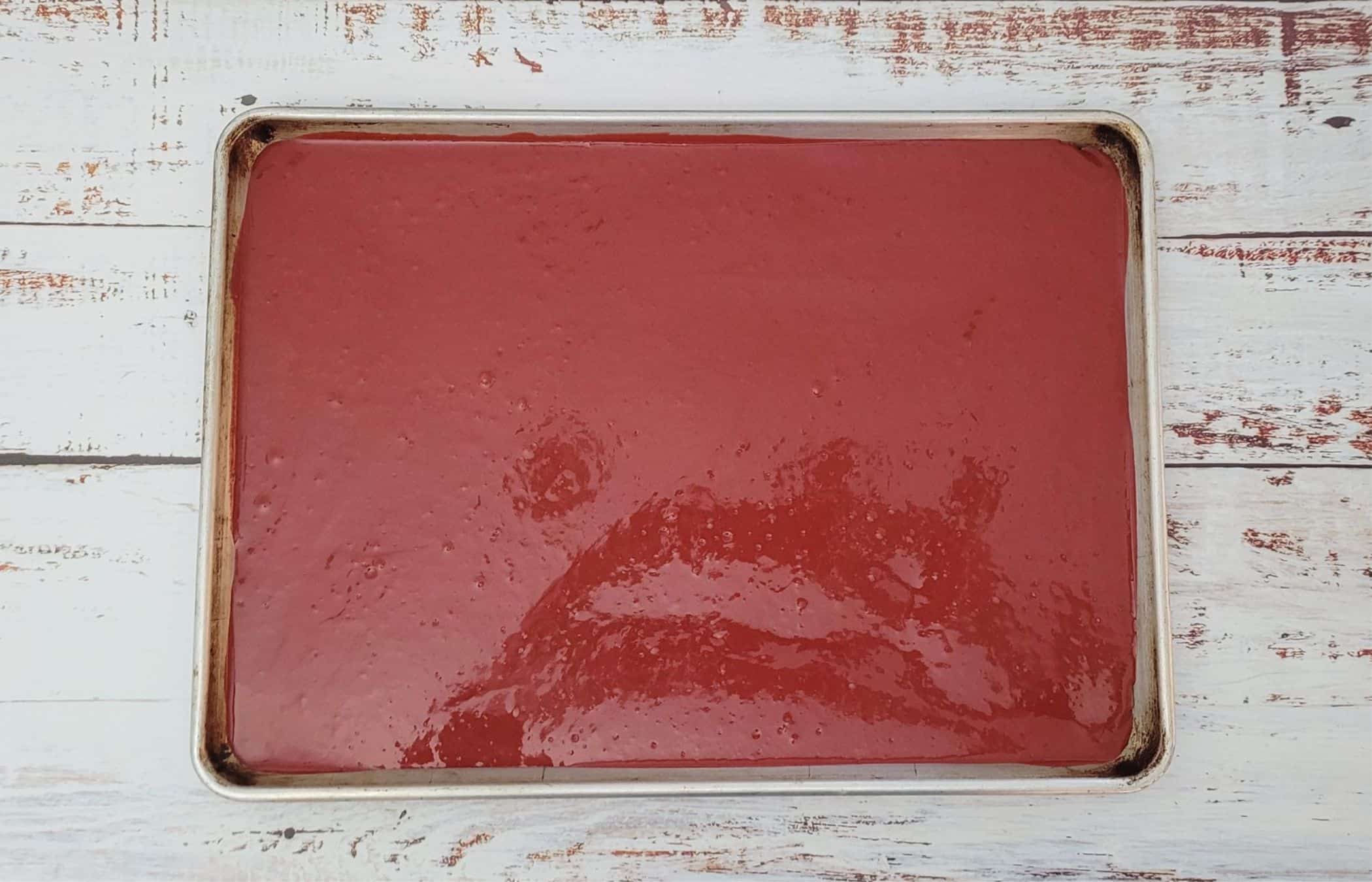 red velvet cake batter poured into a 13" x 9" sheet pan