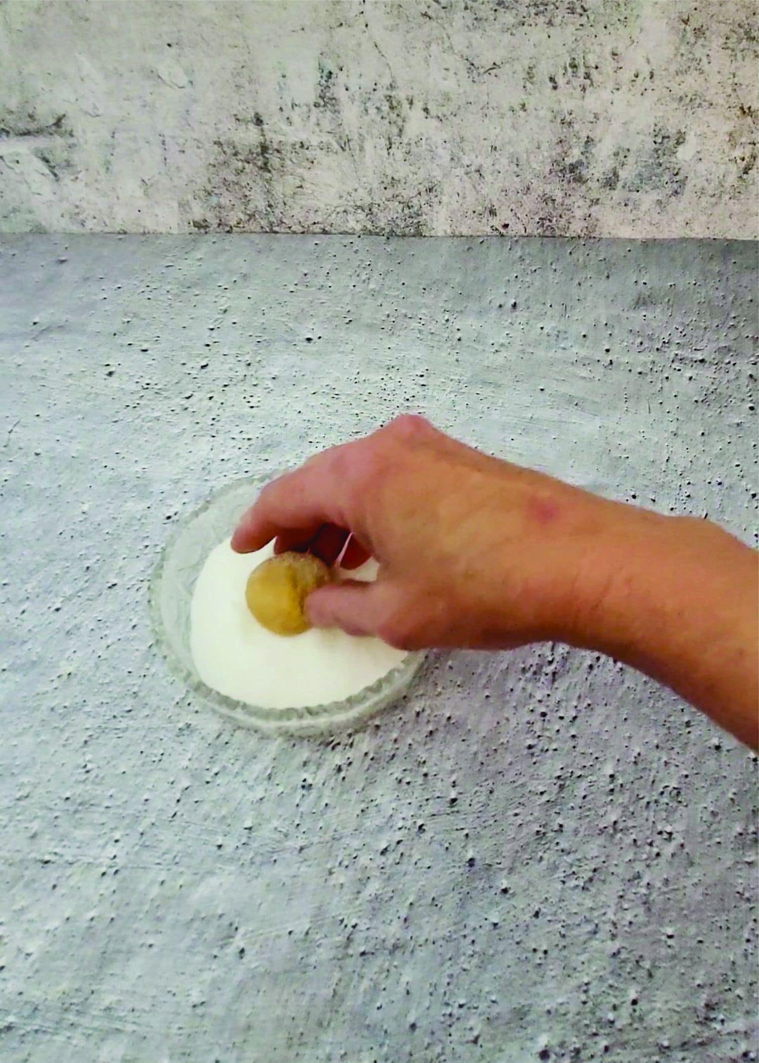 rolling a ball of peanut butter dough in granulated sugar prior to baking to make a crispy cookie