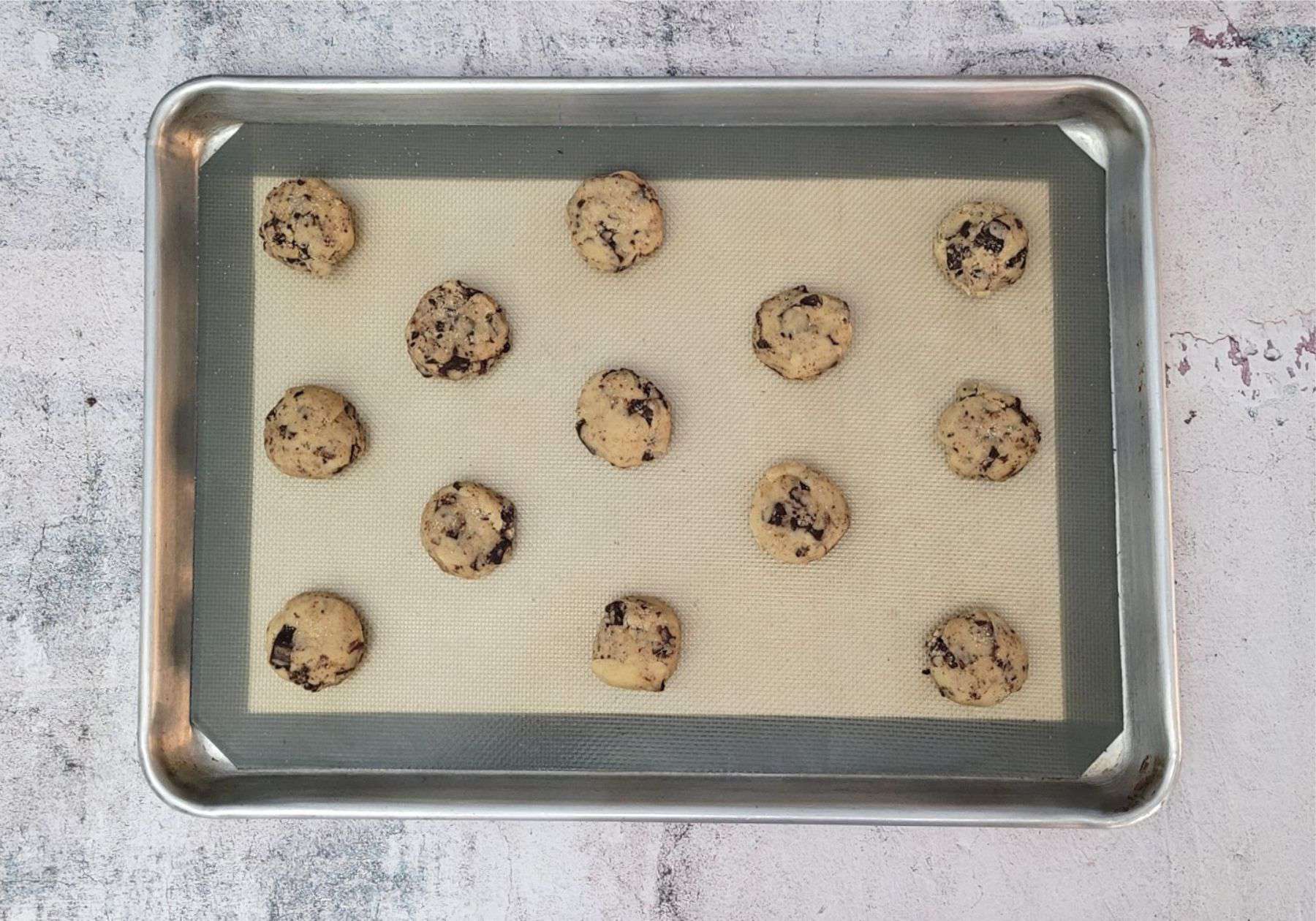 cookie dough scooped onto a sheet pan to prepare for baking