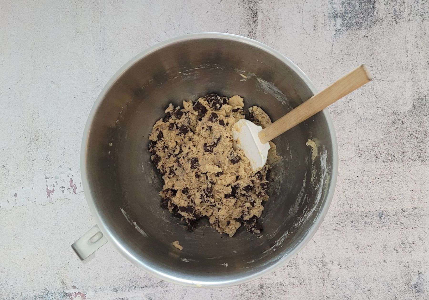 mixing bowl with chocolate chunks stirred into cookie dough