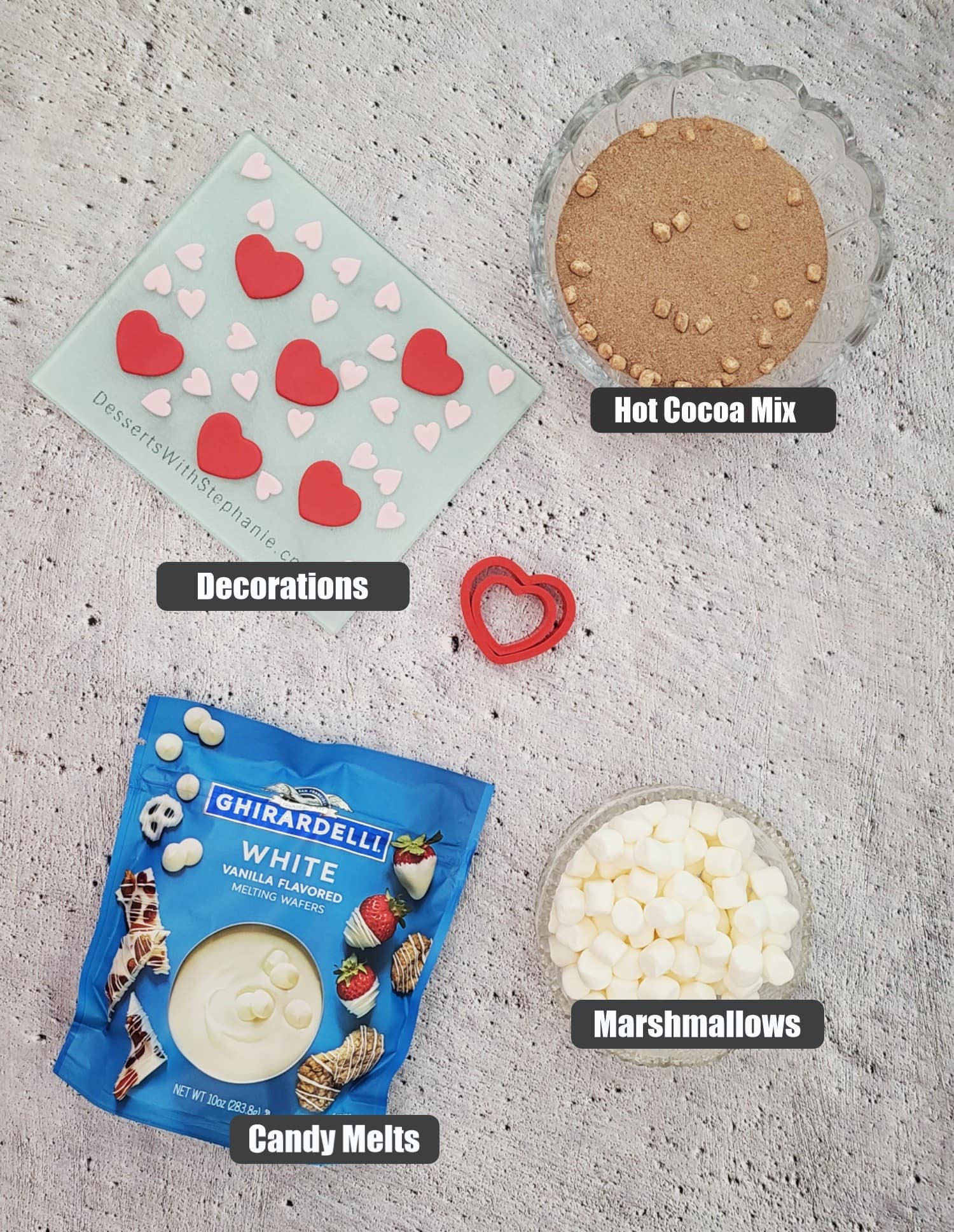 ingredients needed to make hot chocolate bombs for valentine's day including hot cocoa mix, marshmallows, candy melts and decorations