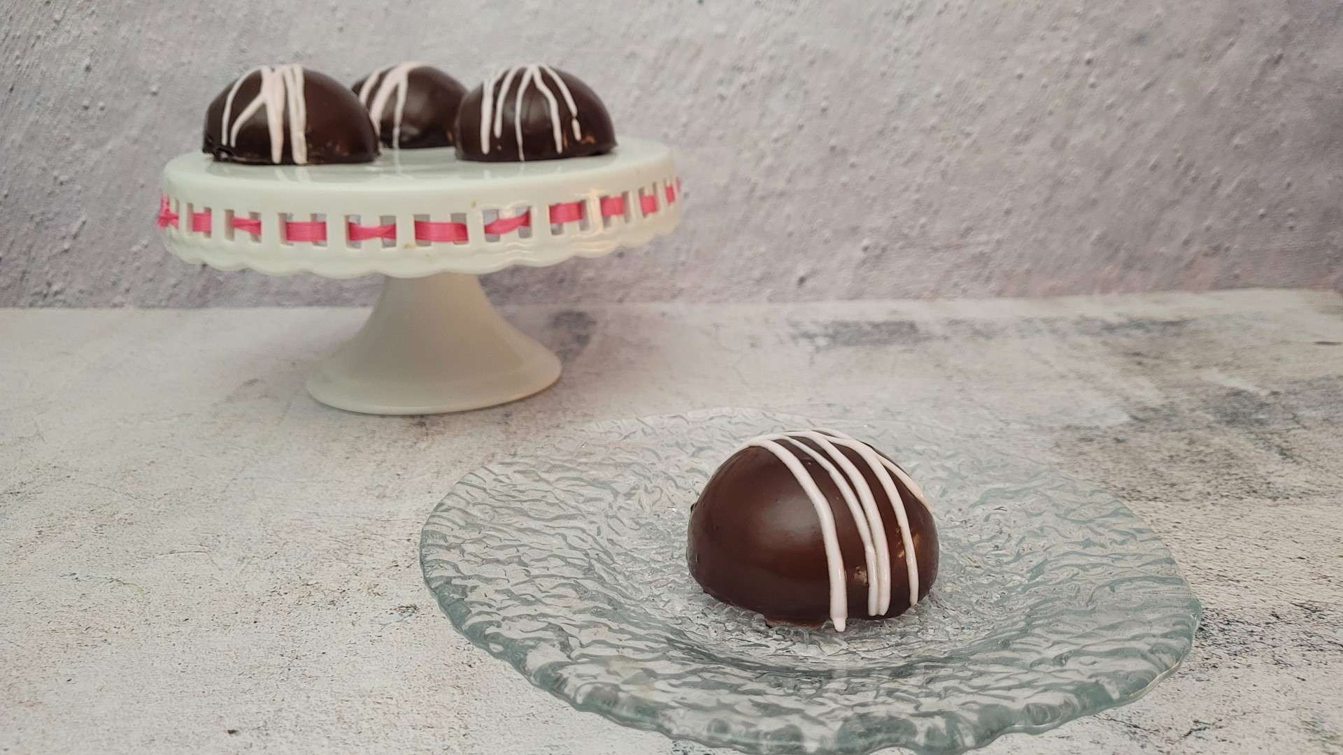 vertical image of a mini Valentines red velvet cake and three cakes on a stand in the background