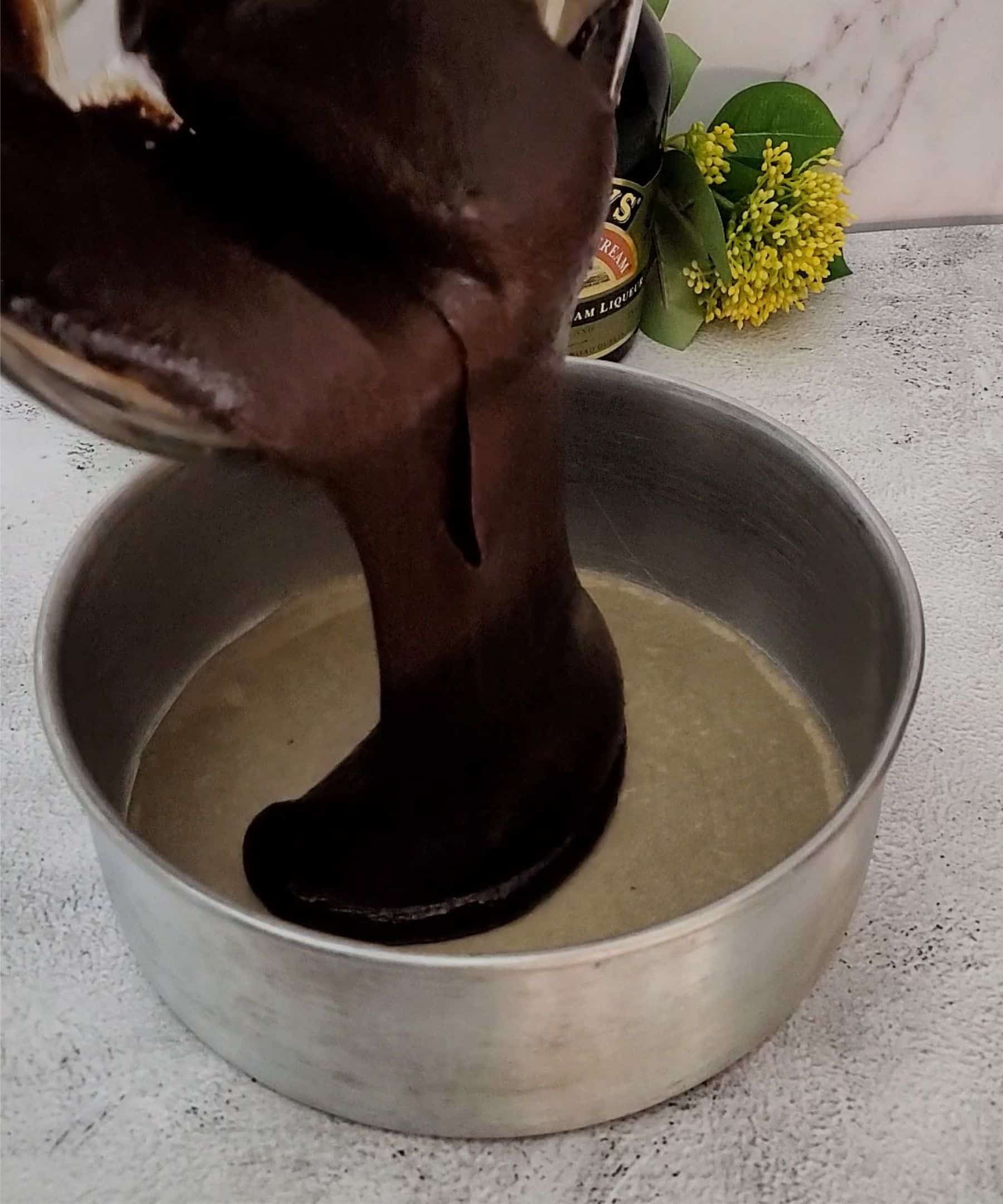 pouring chocolate cake batter with Baileys Irish cream into prepare cake pan