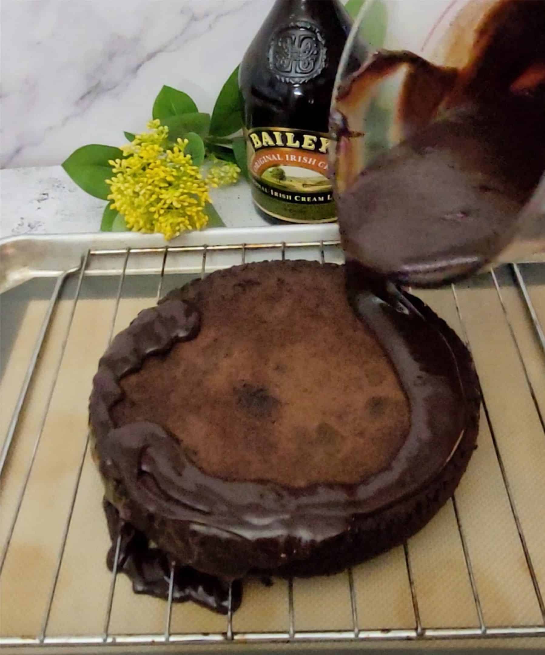 pouring baileys chocolate ganache over a flourless chocolate cake