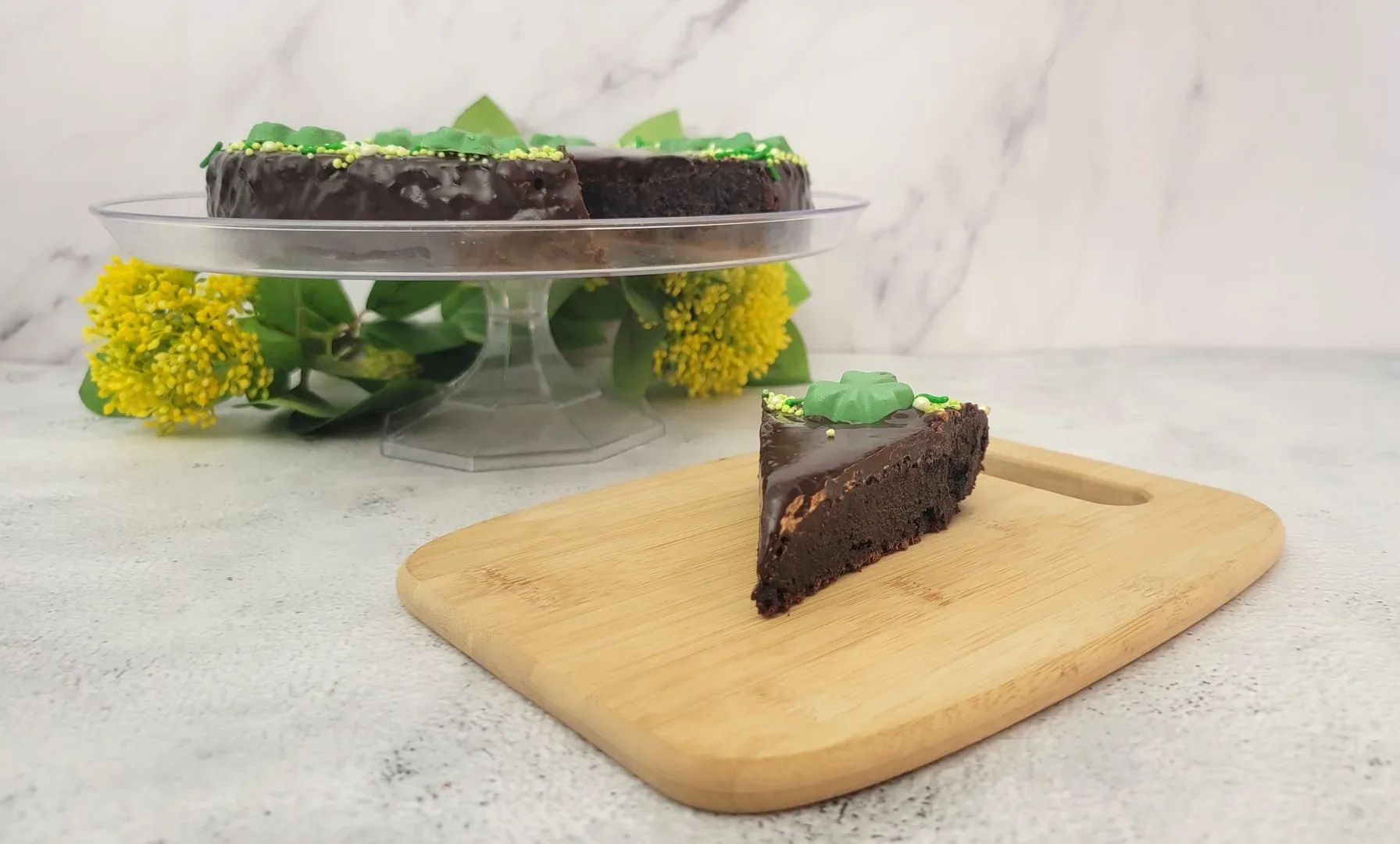 slice of St Patrick's Day flourless cake on a wooden board with the remainder of cake in the background