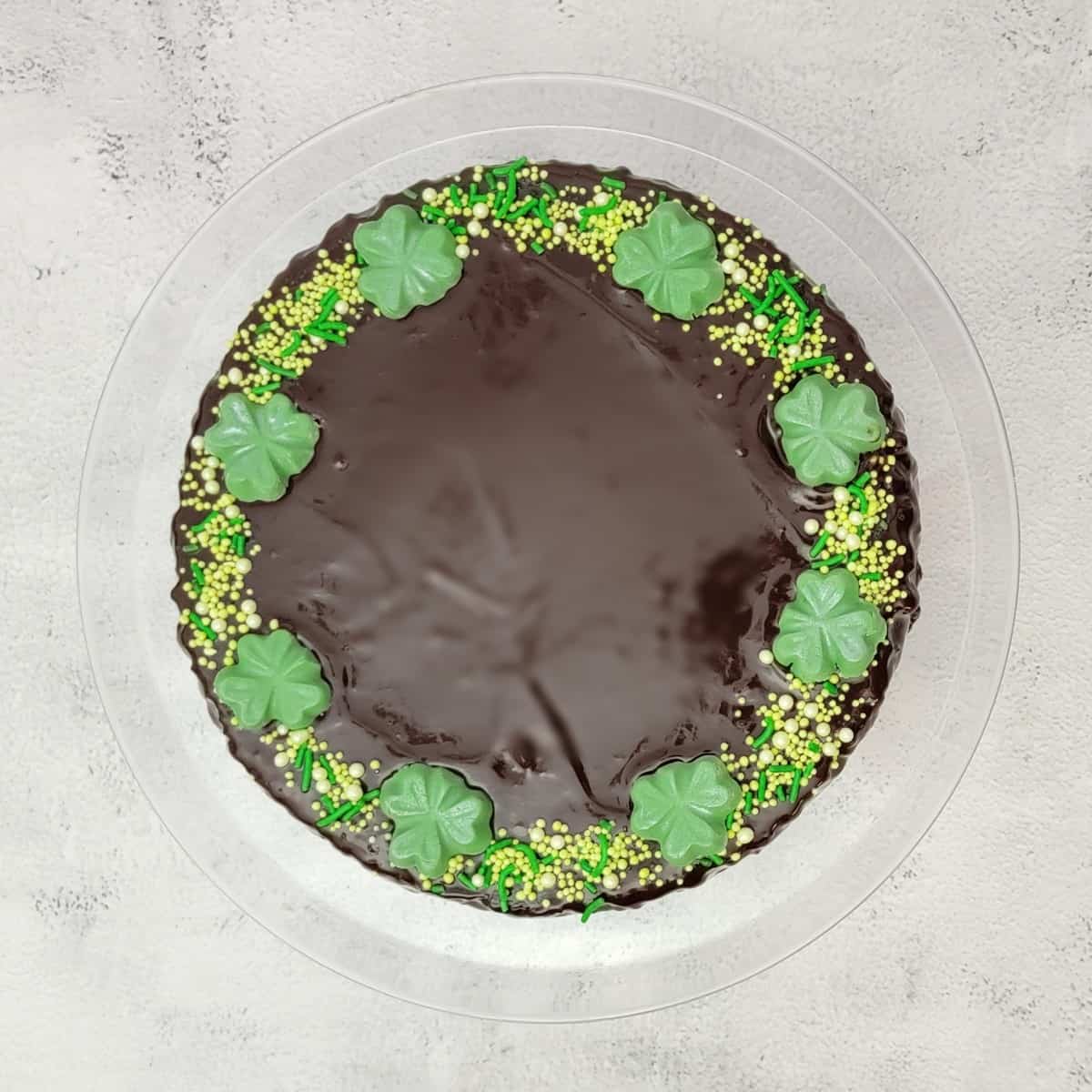 overhead view of St Patrick's Day flourless chocolate cake decorated with green sprinkles and shamrocks