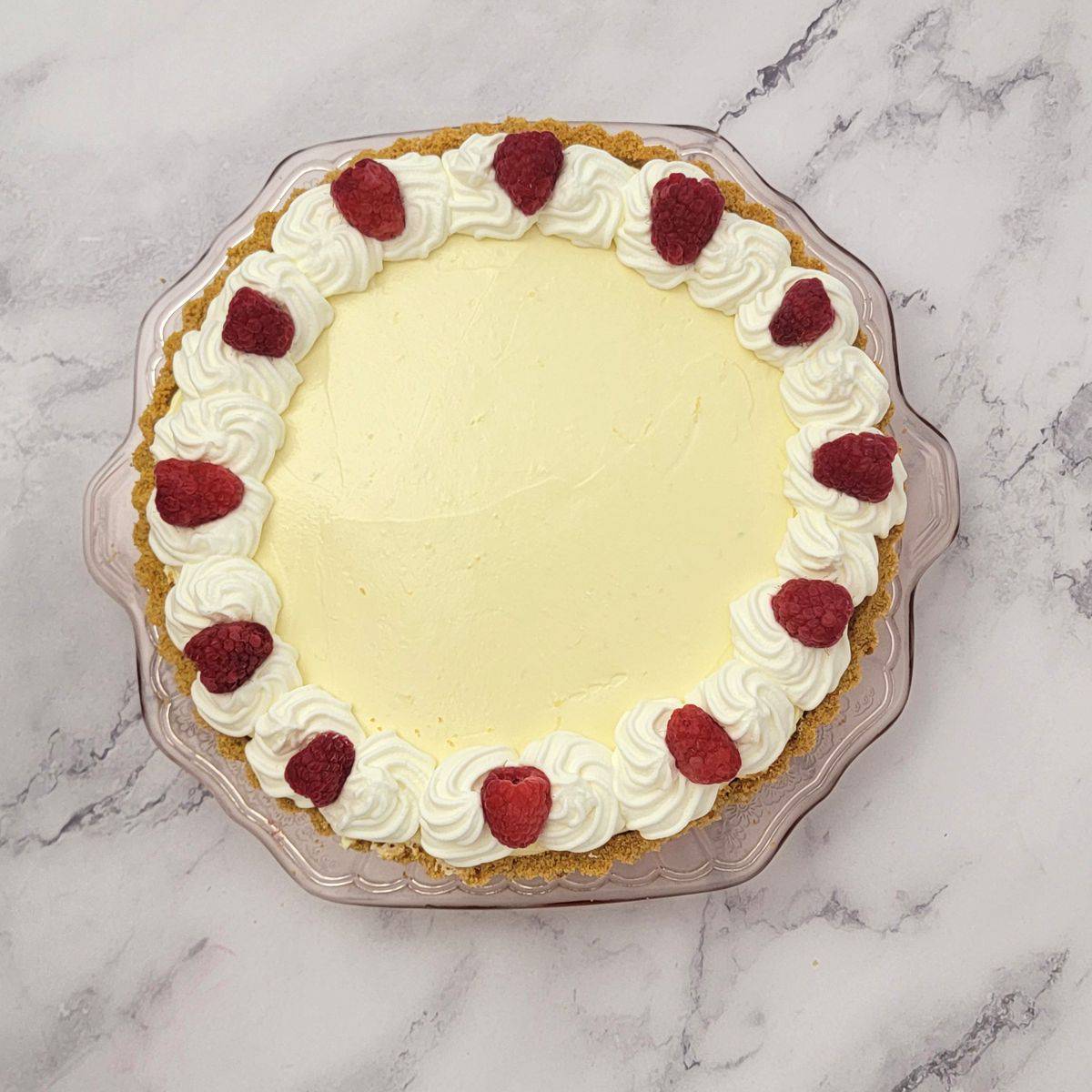 overhead view of lemon cream no bake pie with whipped cream and raspberries