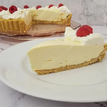 slice of no bake lemon cream pie on a plate with remainder of pie in the background