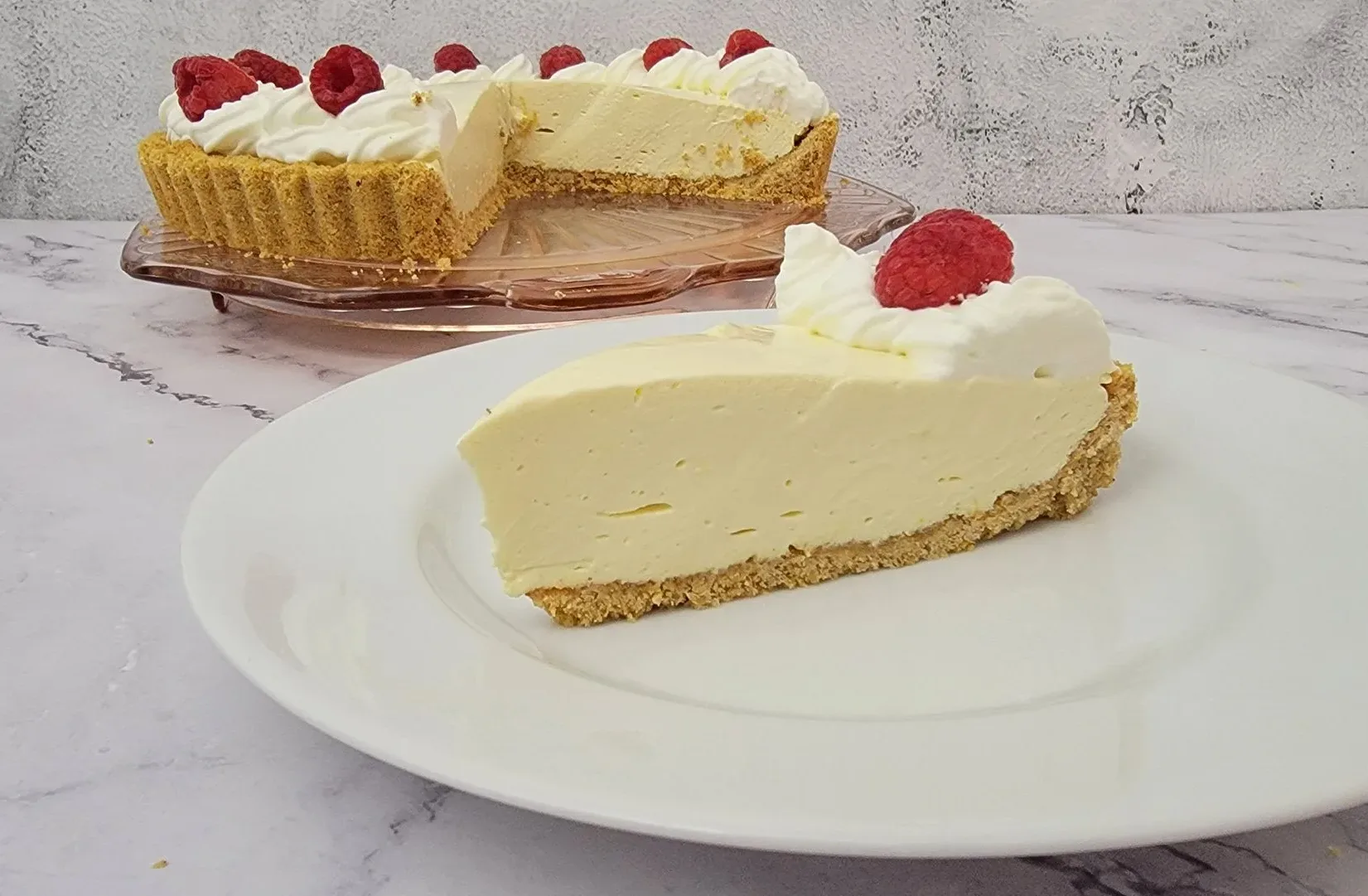 slice of no bake lemon cream pie on a plate with remainder of pie in the background