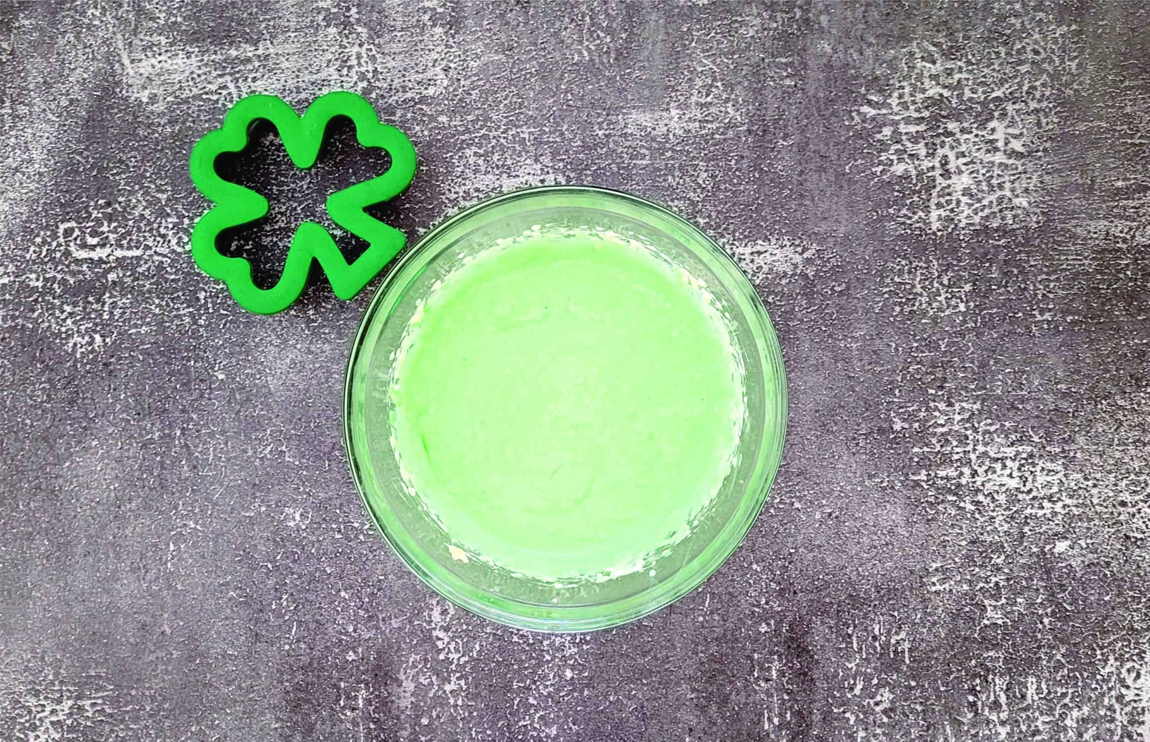 bowl of cream cheese filling and green food coloring to be used to fill puff pastry shamrocks