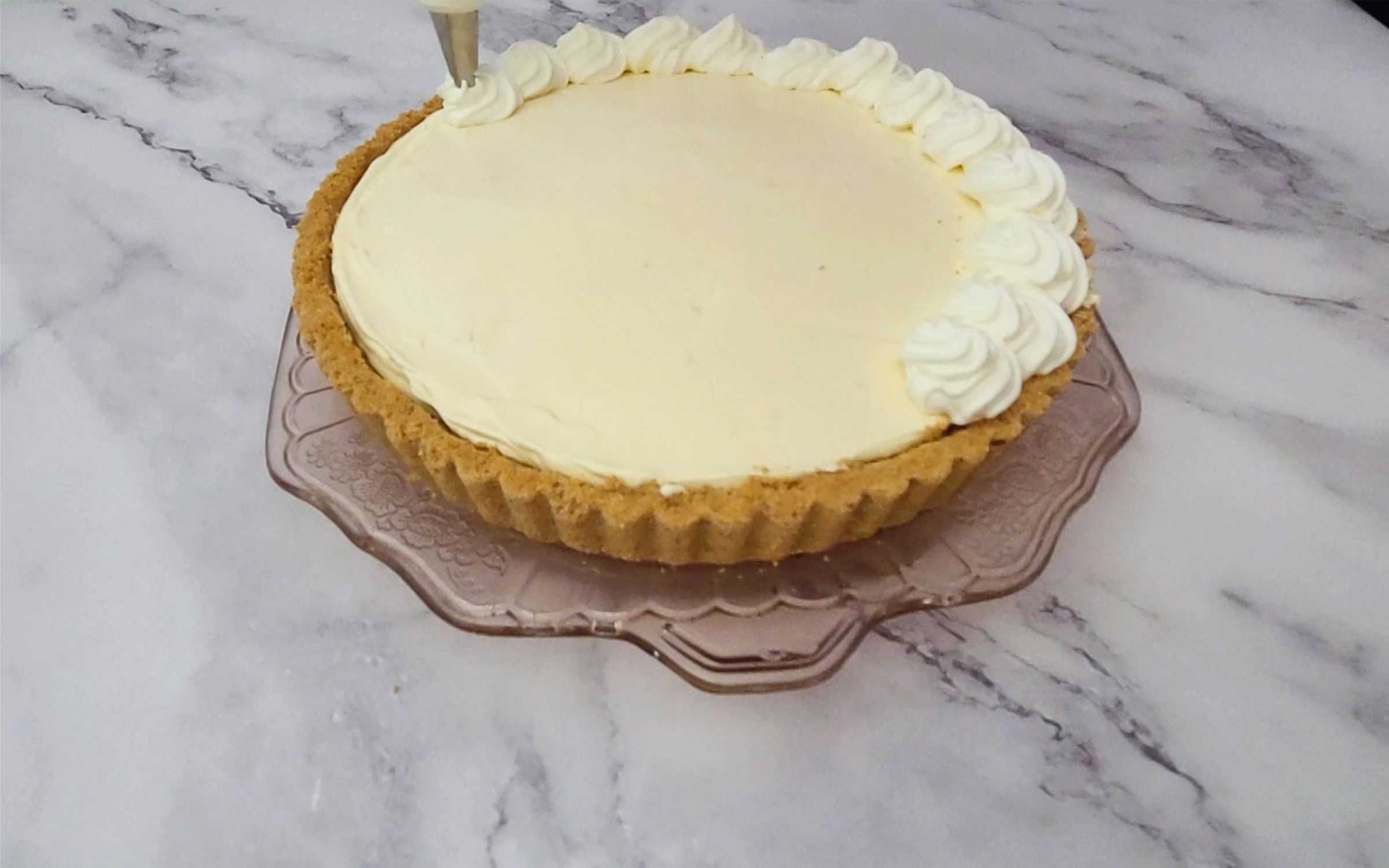 decorating top of no bake lemon pie with whipped cream swirls