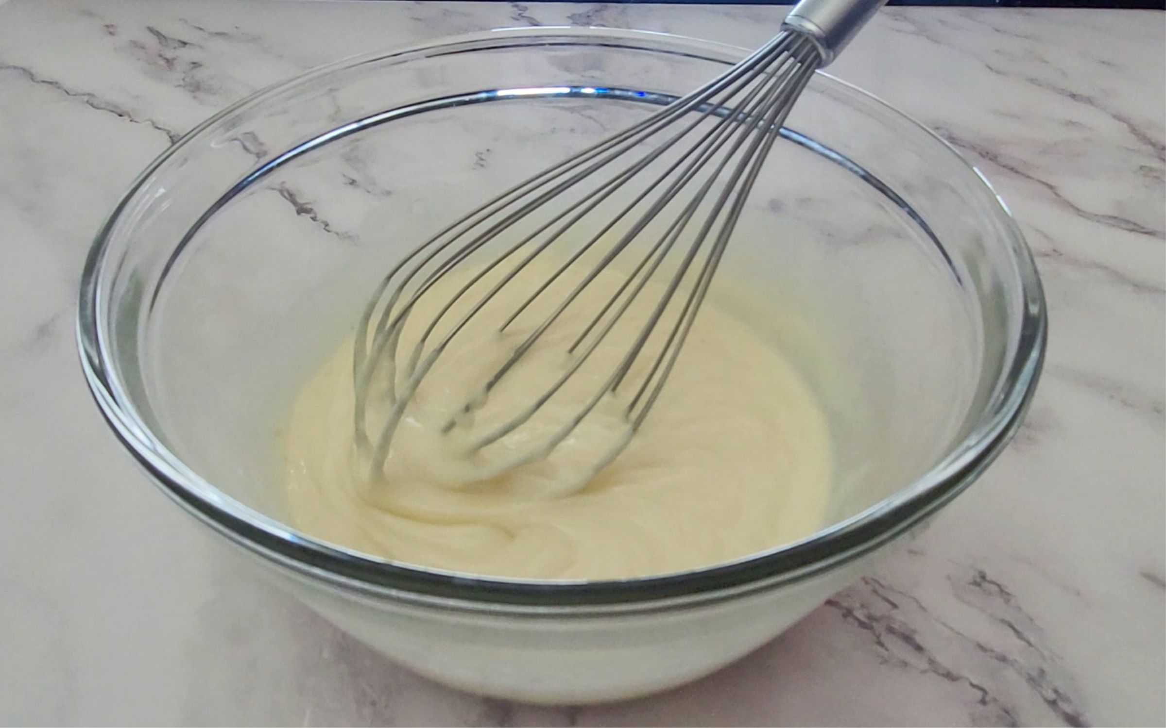 whisk and a bowl with sweetened condensed milk, lemon juice and lemon zest