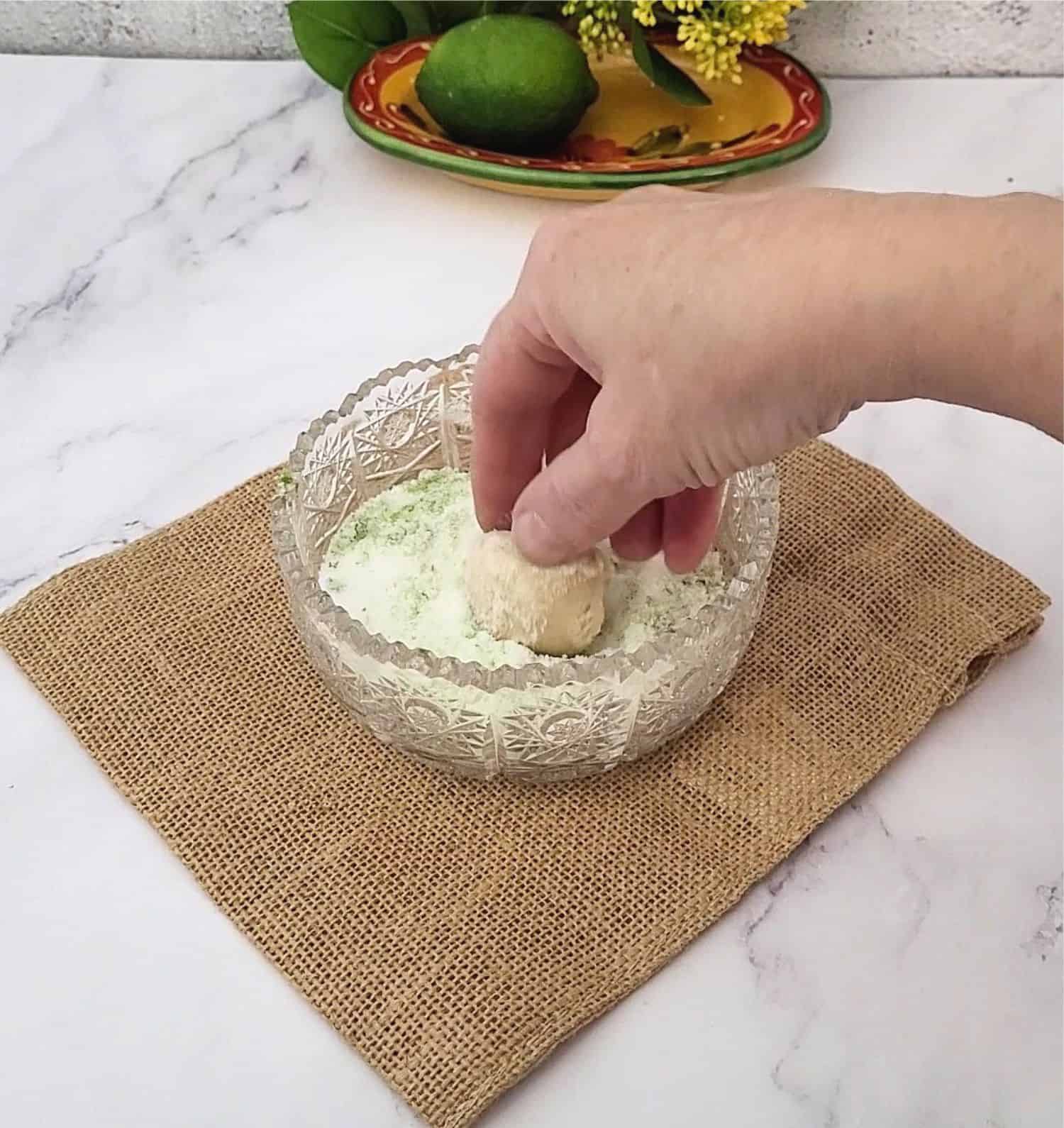 rolling gluten free lime cookie in a lime flavored sugar mixture